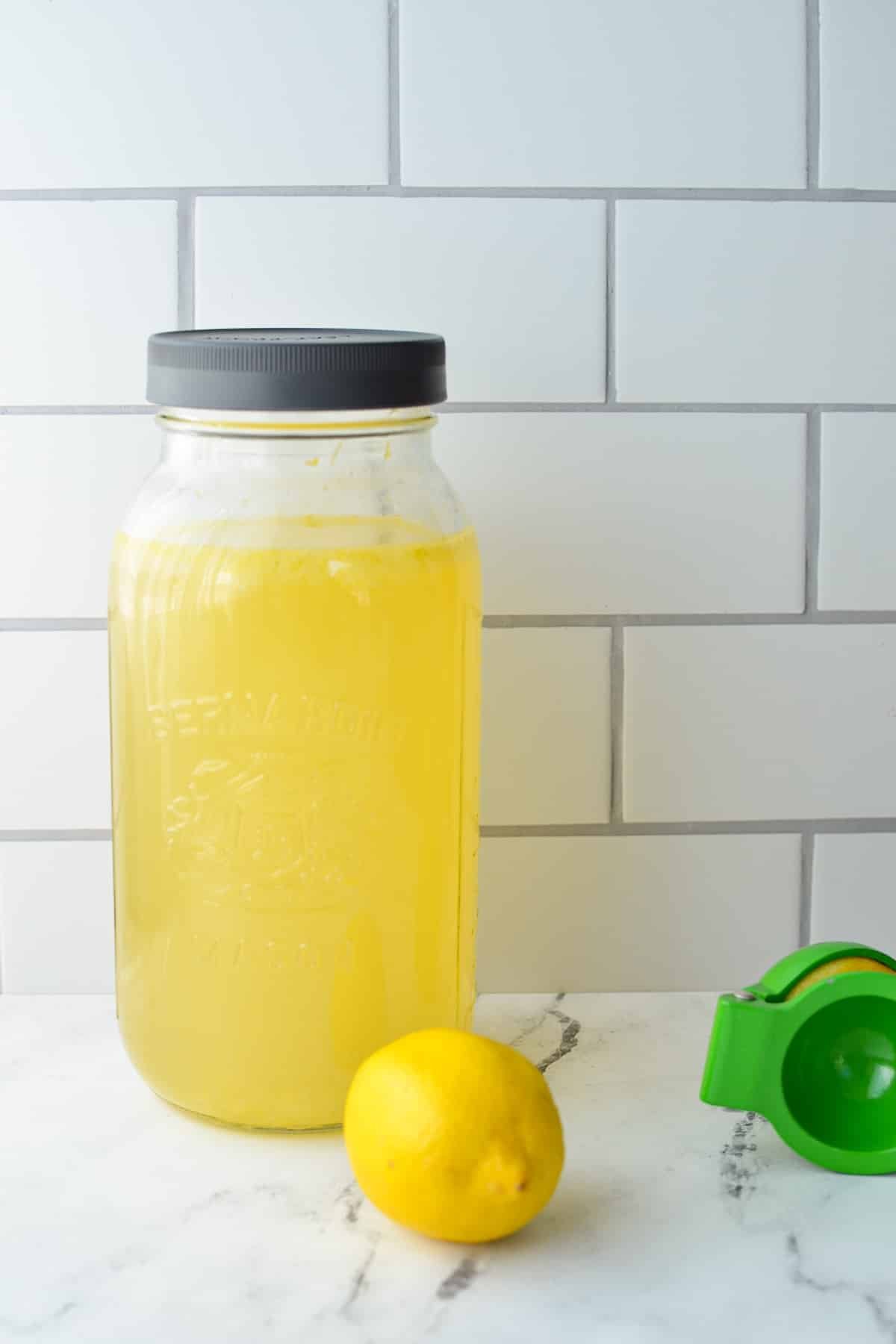 A half gallon mason jar of lemon and ginger water resting on a counter.