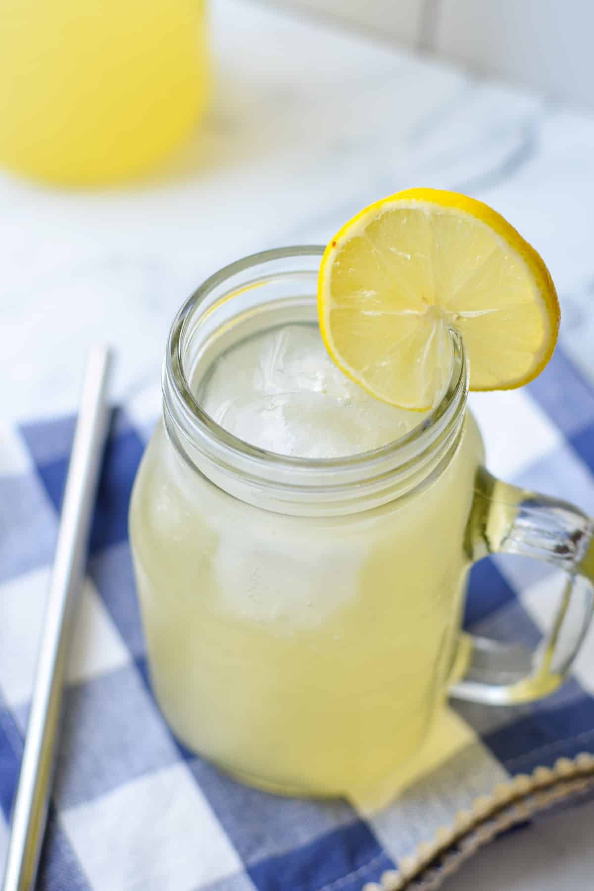A close up of a jar filled with a lemon based beverage.