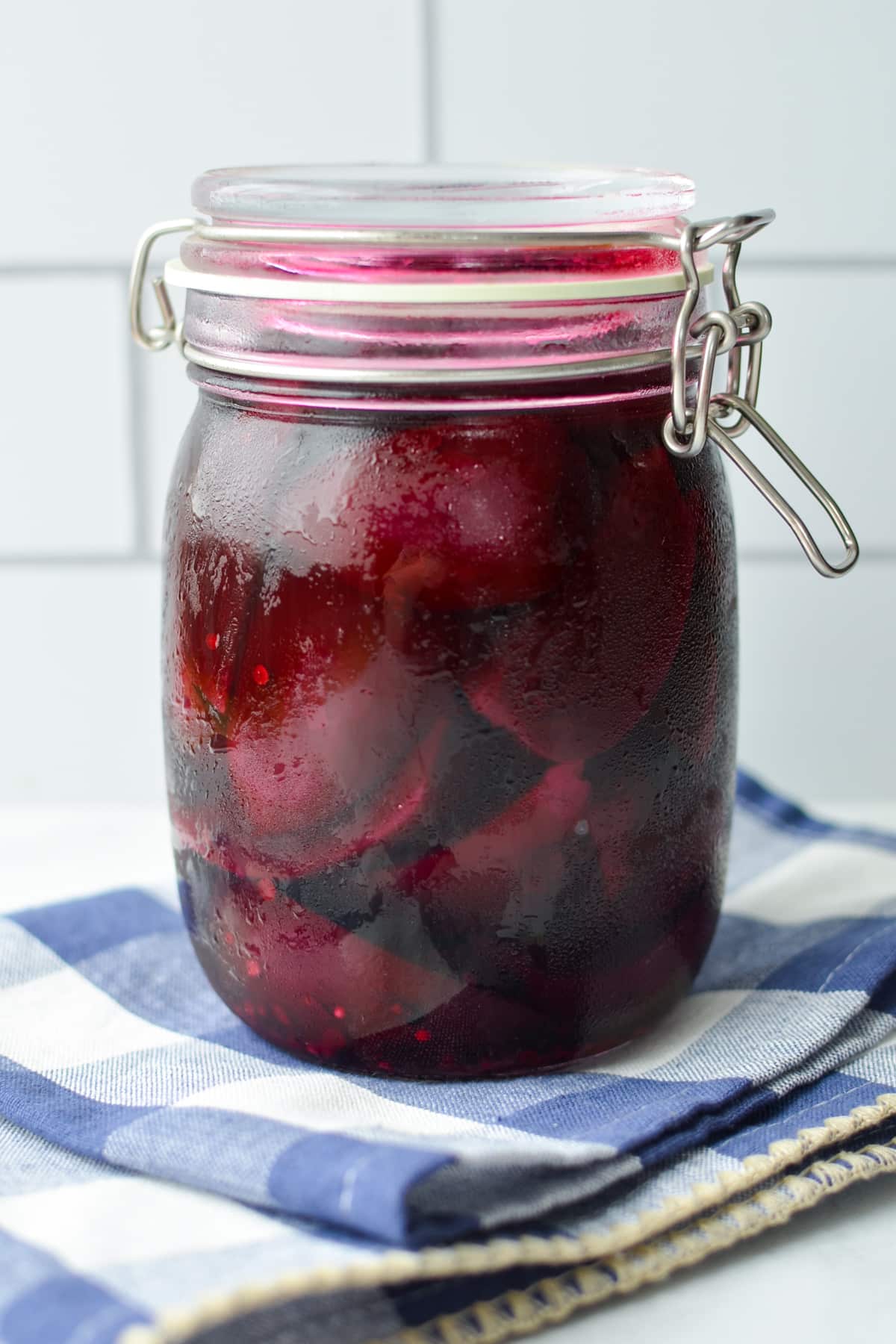 A jar of pickled beets resting on a cloth.