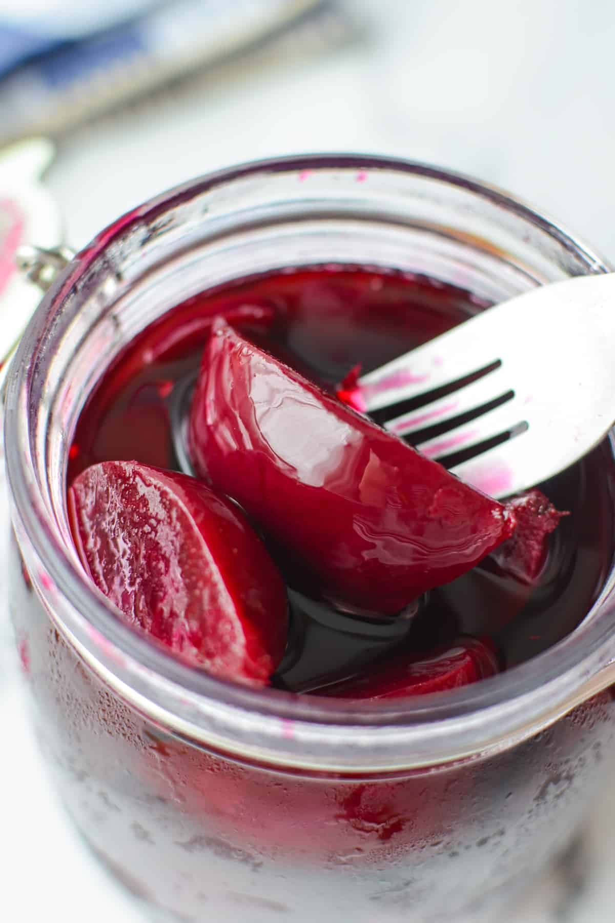 A jar of pickled beets with a fork removing a piece.
