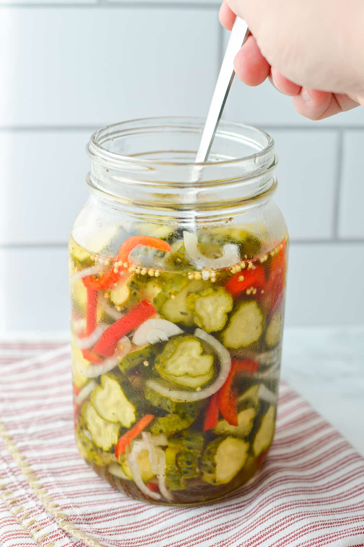 A jar of refrigerator pickles with a fork removing some.