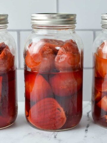 Three jars of beets lined up on a countertop.