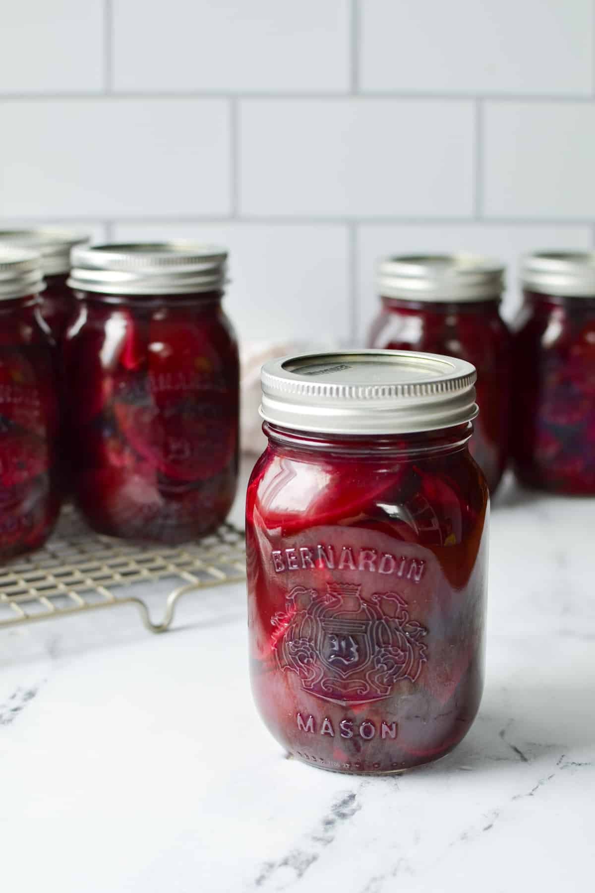 A jar of canned beets with other jars in the background.