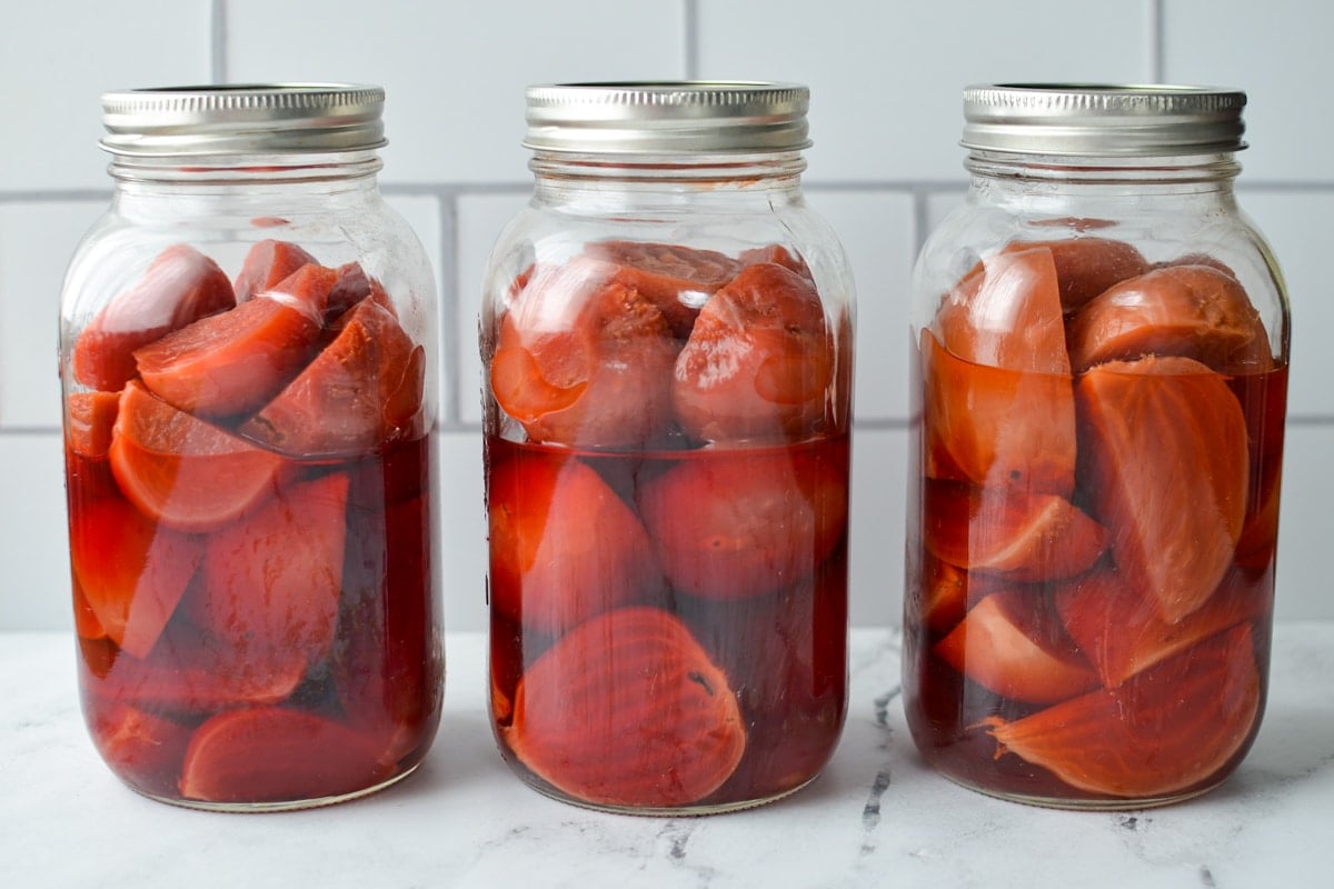 Three jars of pressure canned beets on a counter.