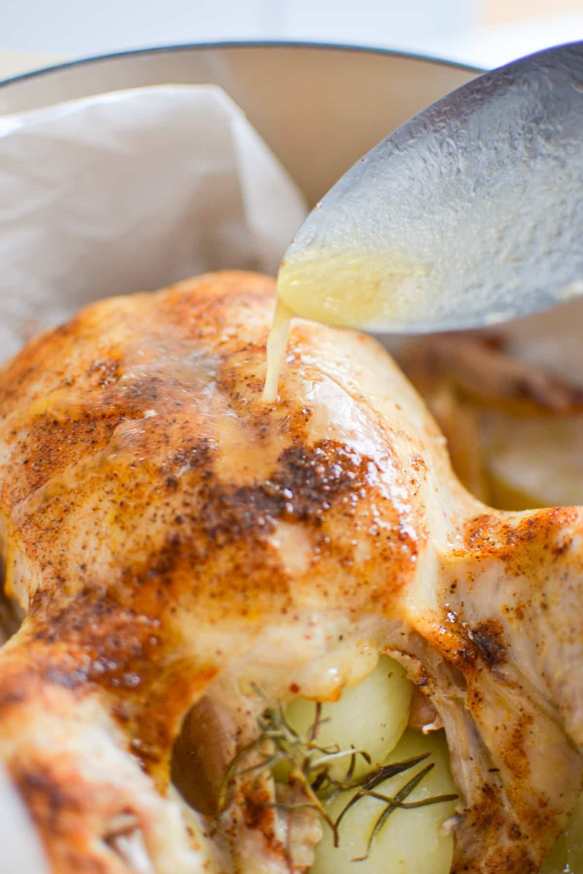 Drizzling pan juices over a whole roast chicken.