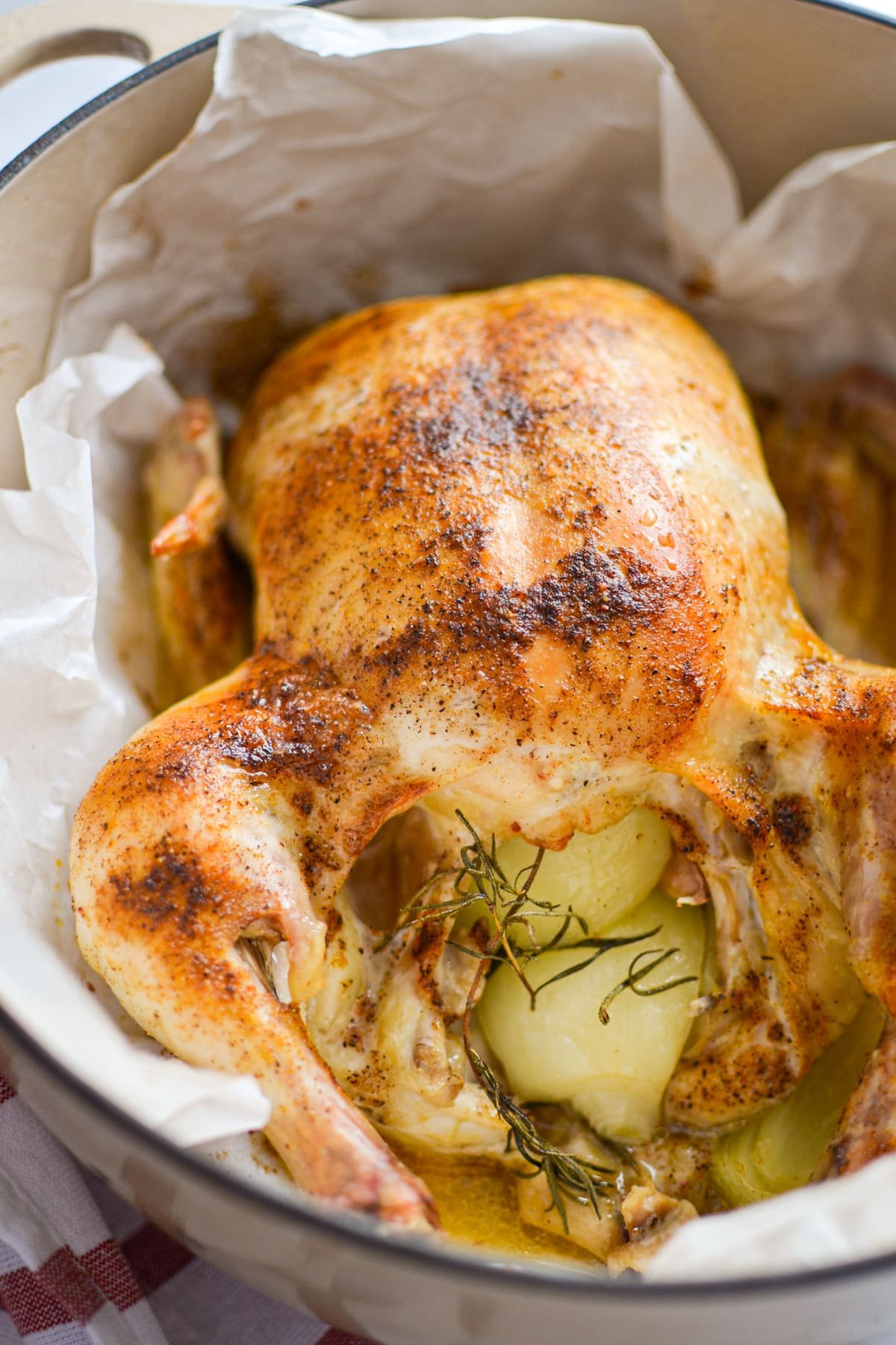 A whole chicken in a parchment lined Dutch Oven.