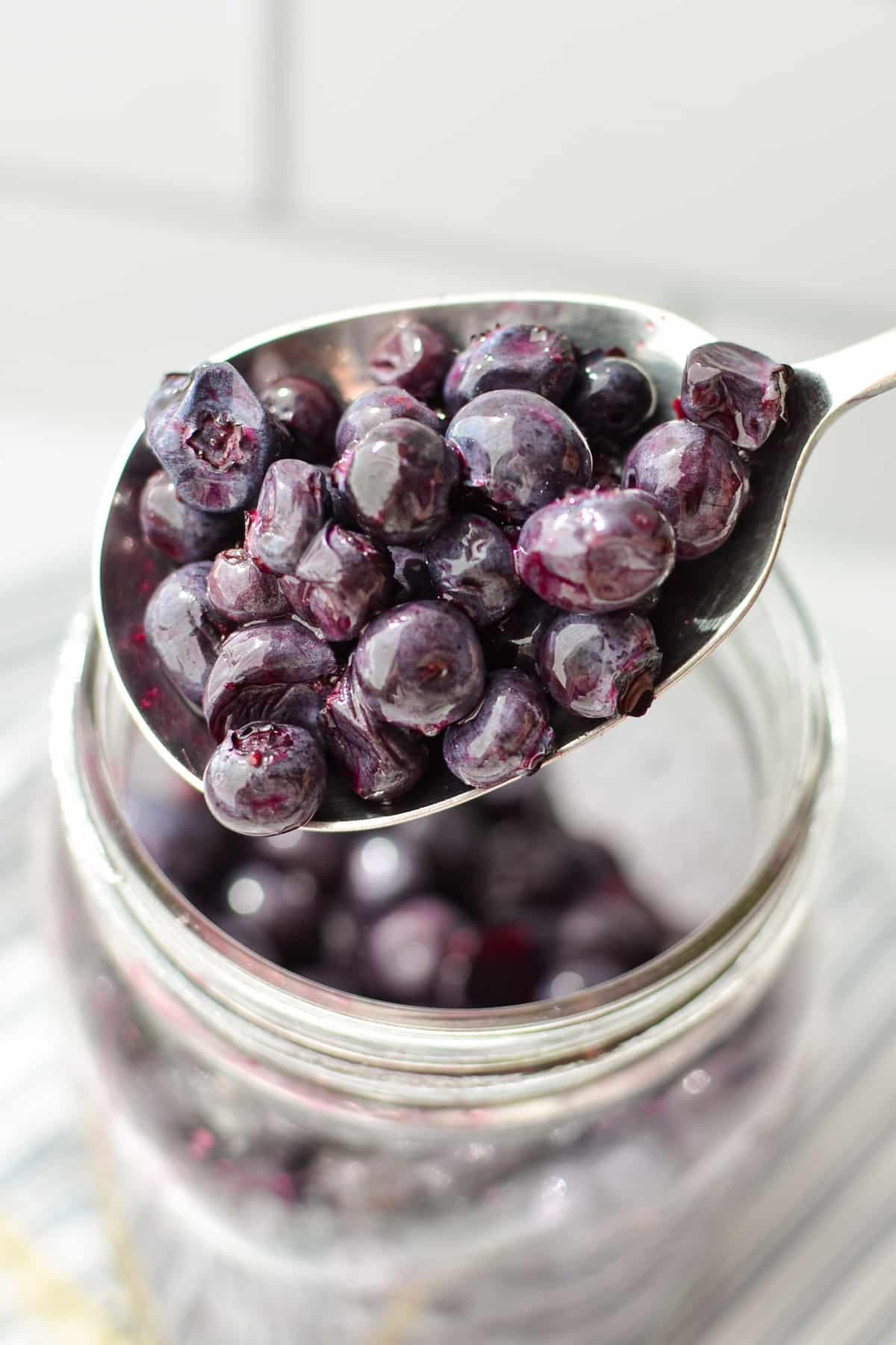 A spoonful of blueberries from a jar.
