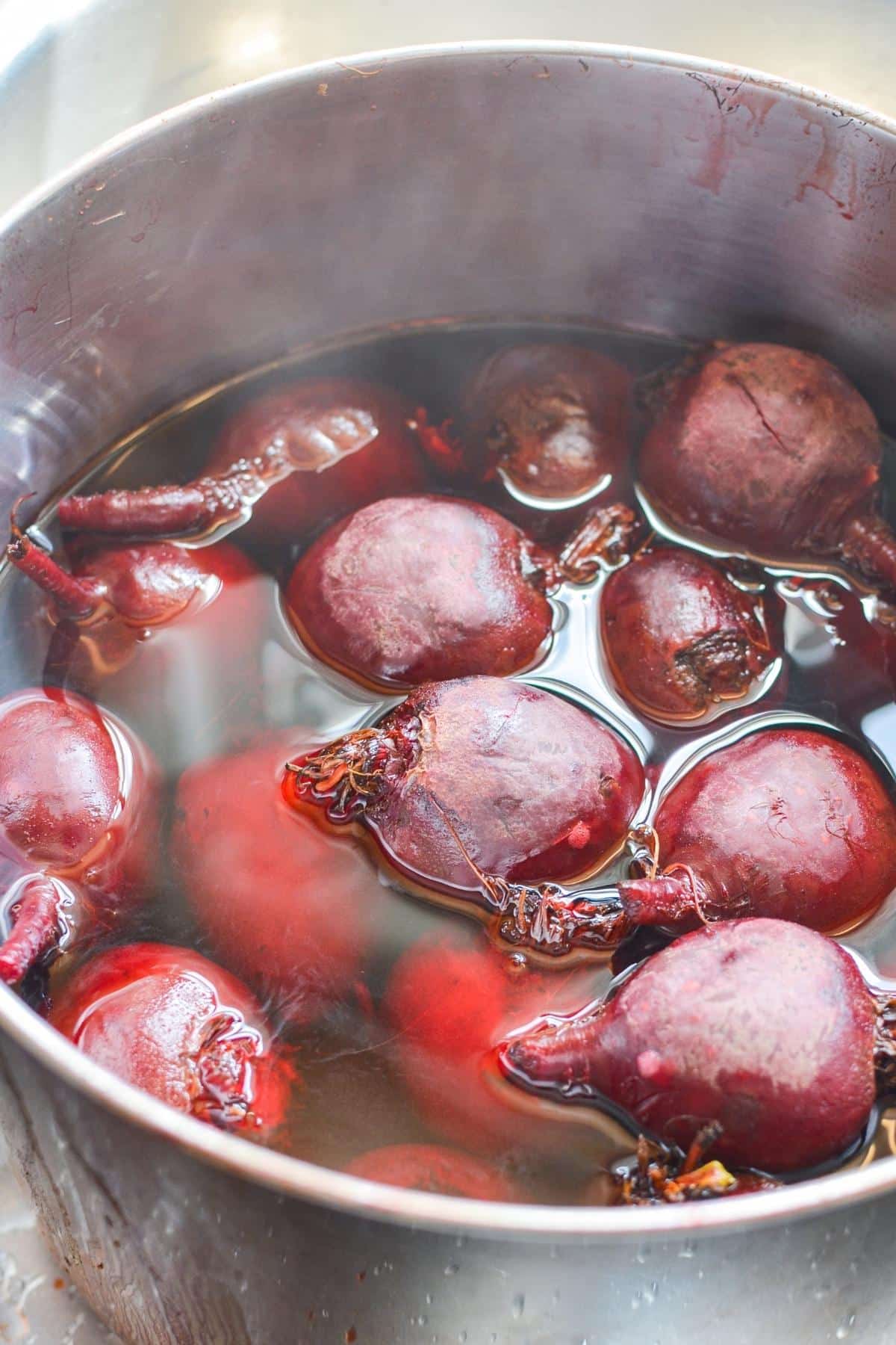 A pot of cooked beets in water.