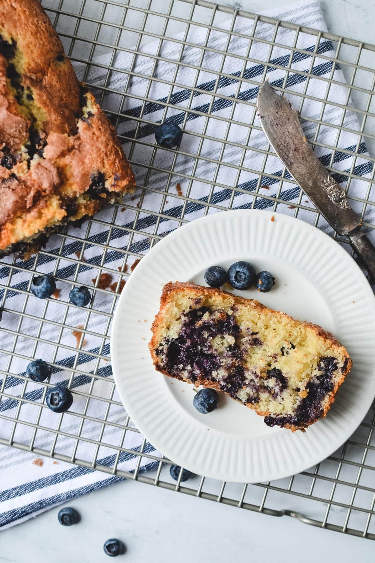 A slice of blueberry bread on a white plate.