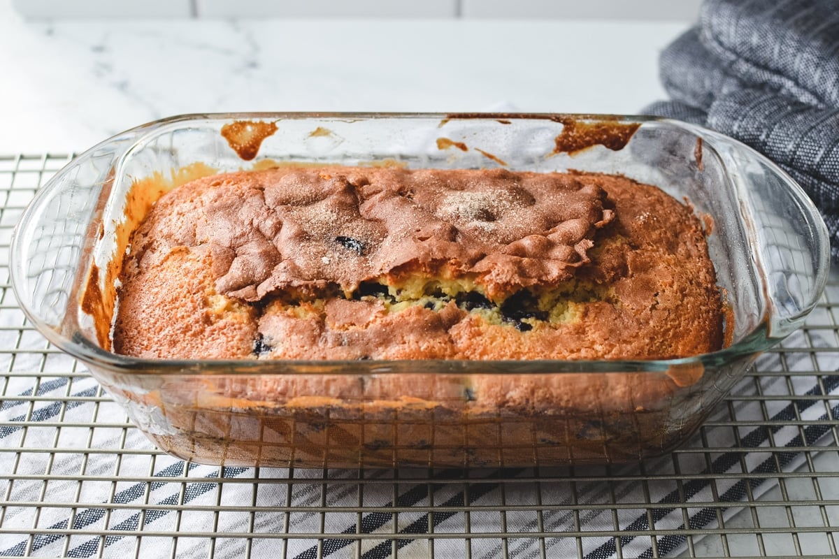 A loaf of quick bread in a pan on a wire rack.