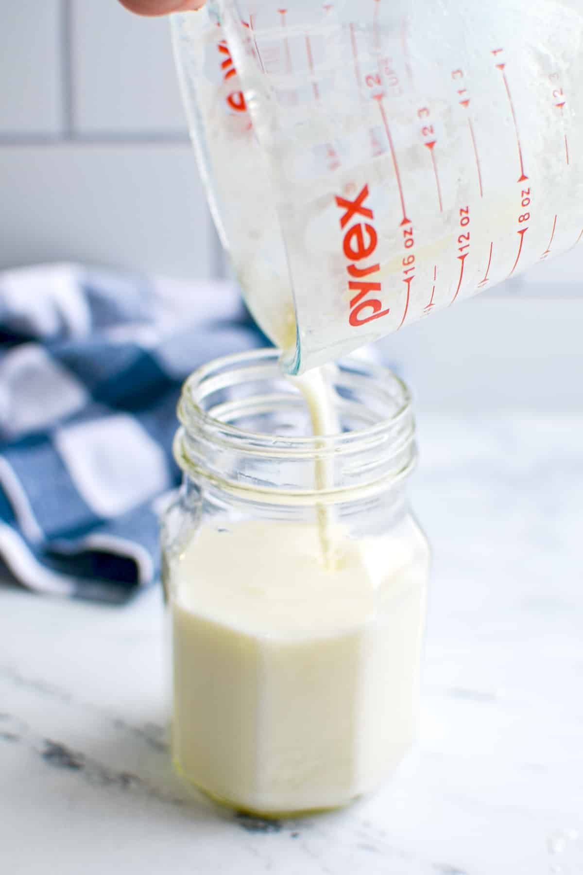 A jar with kefir being poured into it.
