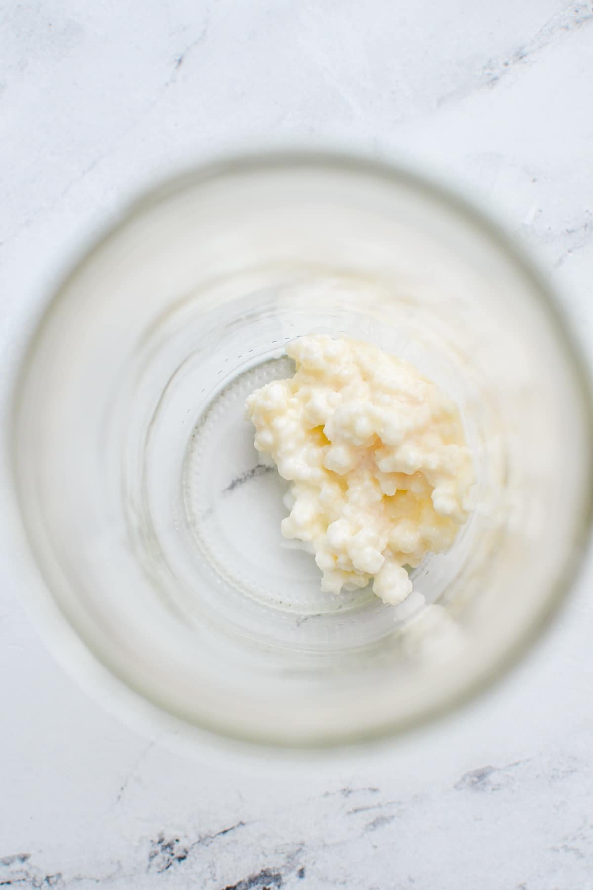 Adding kefir grains to a glass jar.