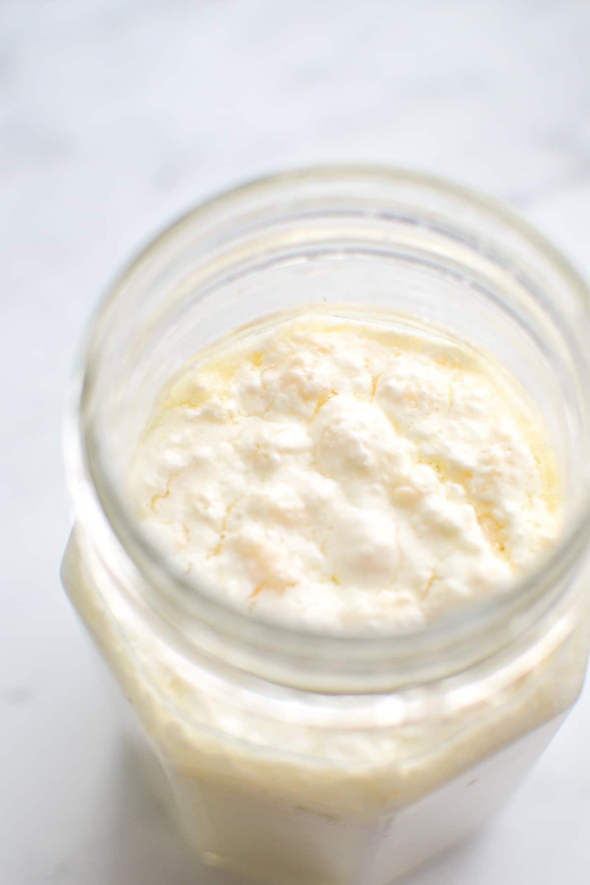 A jar of kefir with the grains floating on top.