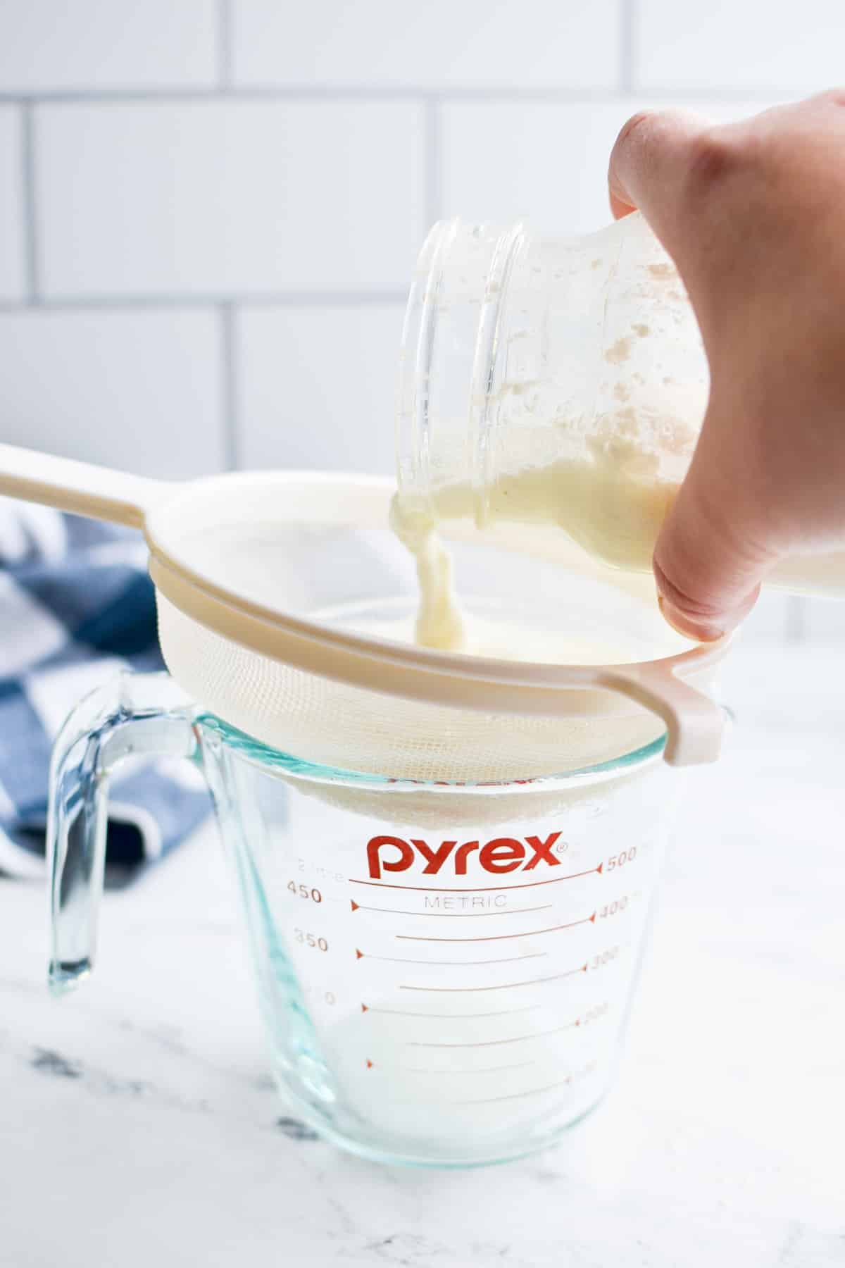 Pouring kefir into a strainer.