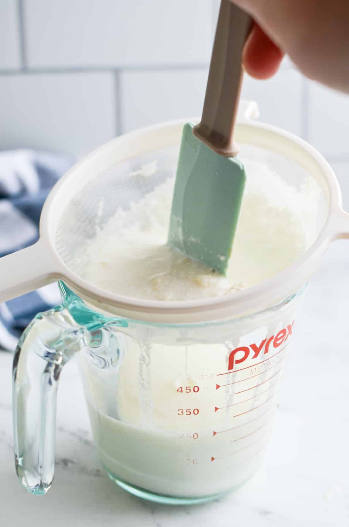 Working cultured milk through a strainer.