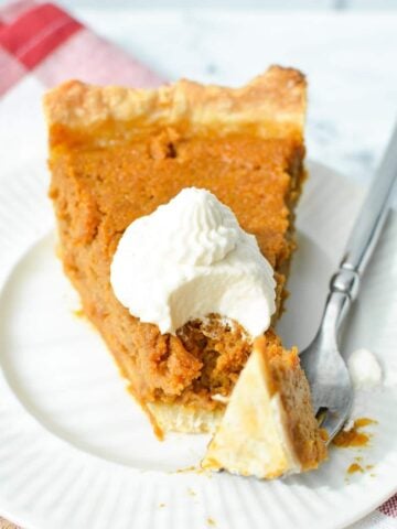A slice of pumpkin pie topped with whipped cream.