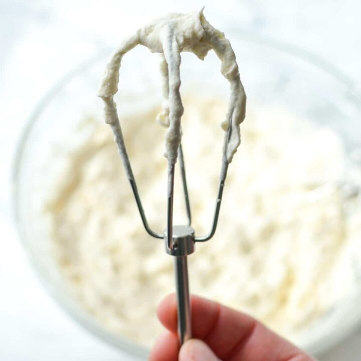 A whisk with whipped cream on it.