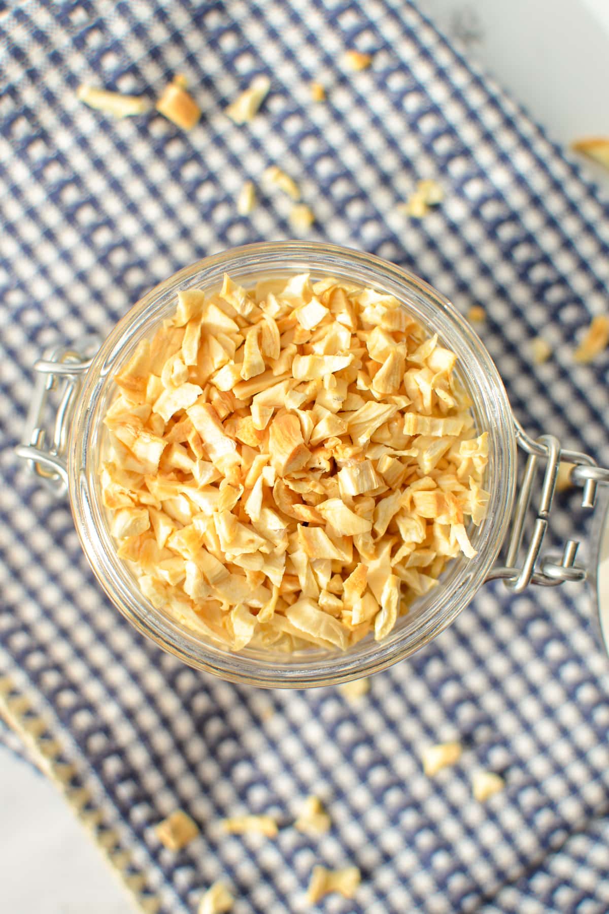 A jar of dried minced garlic on a blue patterned napkin.