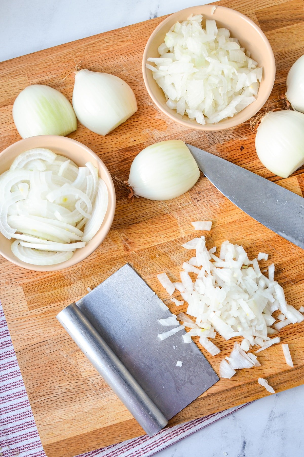 A cutting board with chopped and sliced onions.