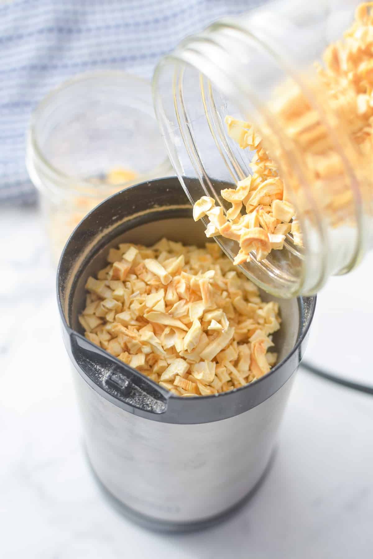 Adding dried garlic to a coffee grinder to make powder.