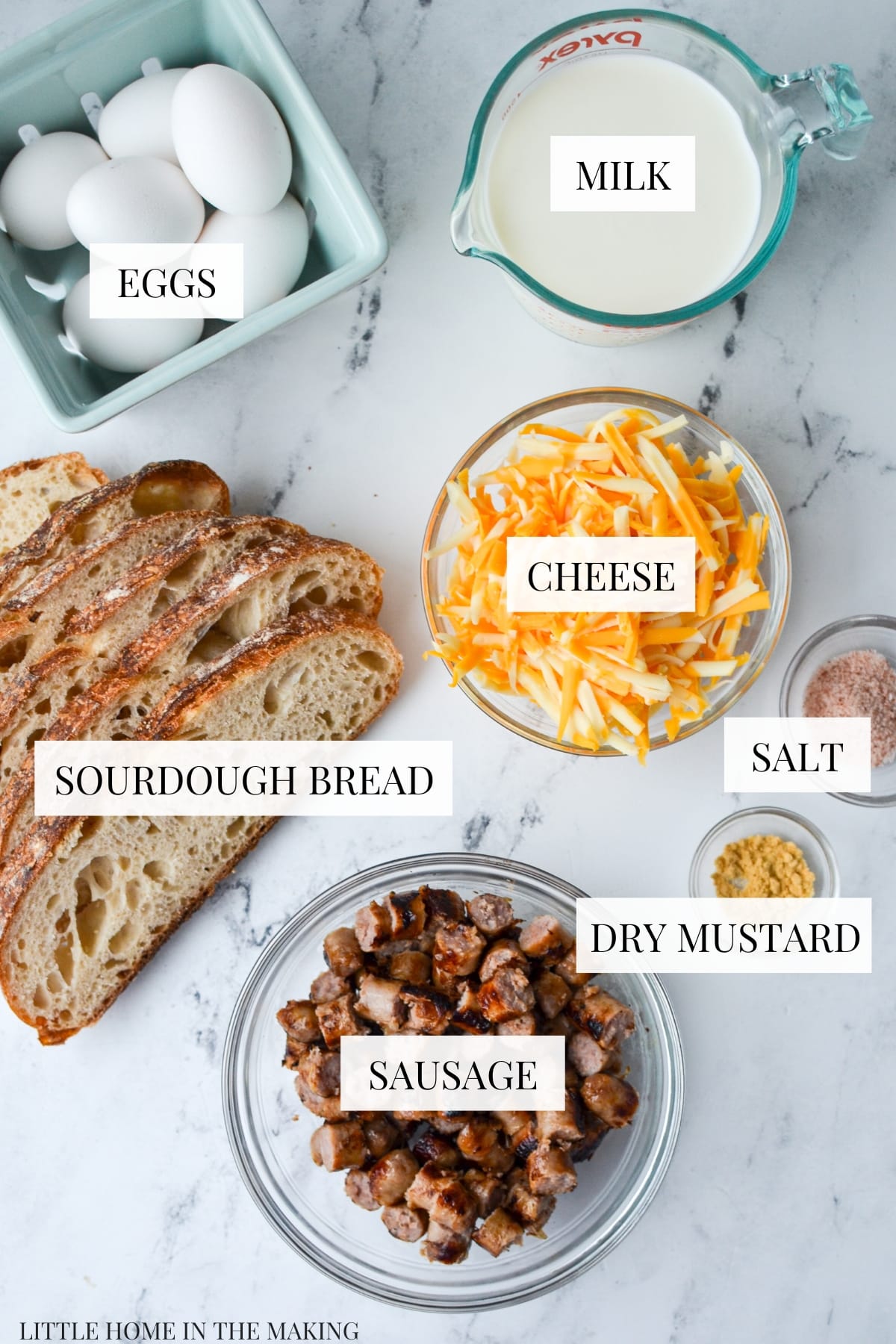 The ingredients needed to make a breakfast casserole: sourdough bread, cheese, sausage, eggs, and milk.