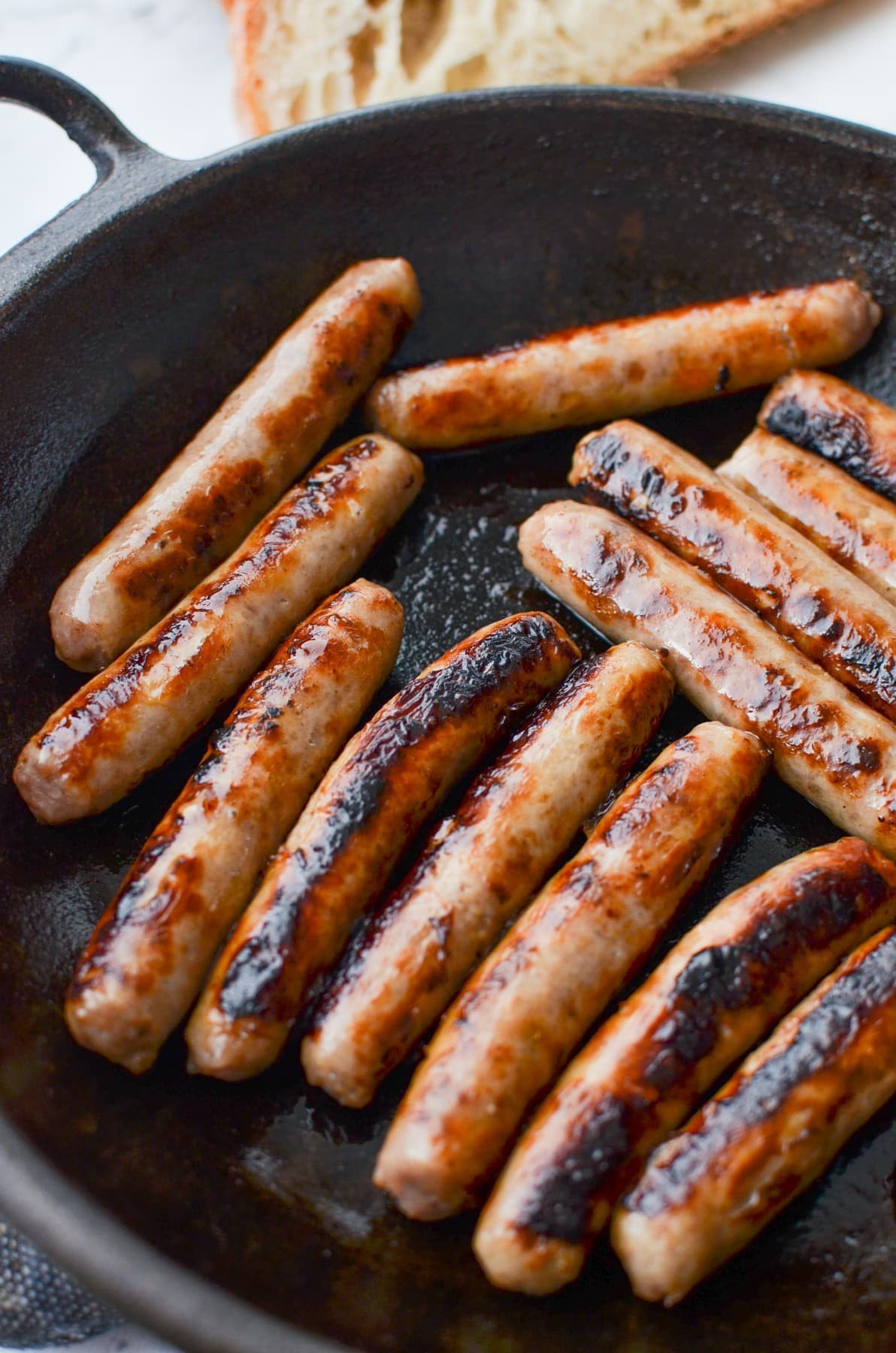 A cast iron skillet filled with cooked sausages.