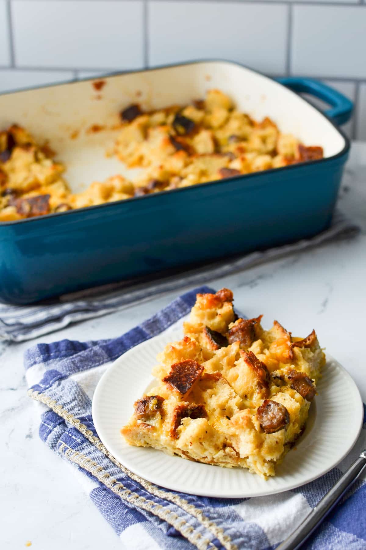 A slice of breakfast casserole with the baking dish in the background.