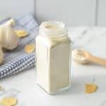 A jar of garlic powder with garlic cloves in the background.