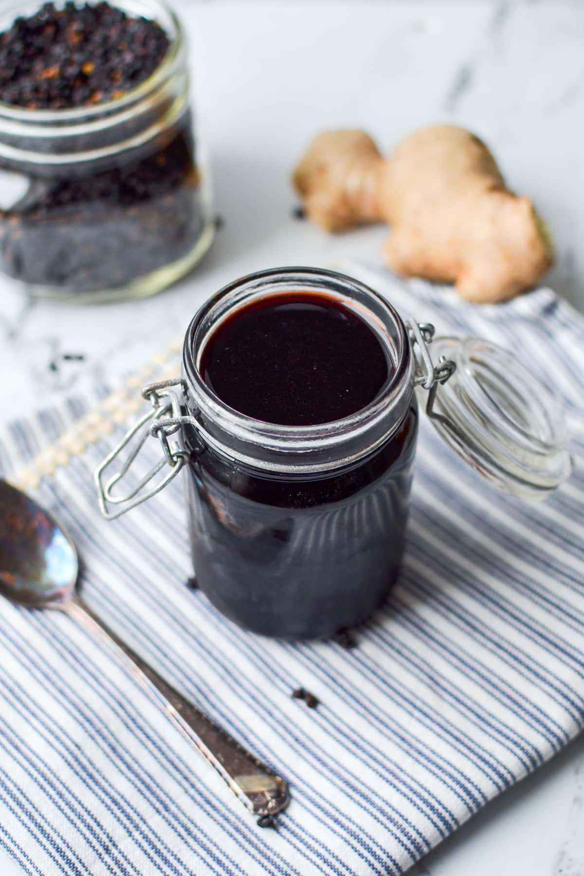 A jar of elderberry syrup resting on a blue striped napkin.