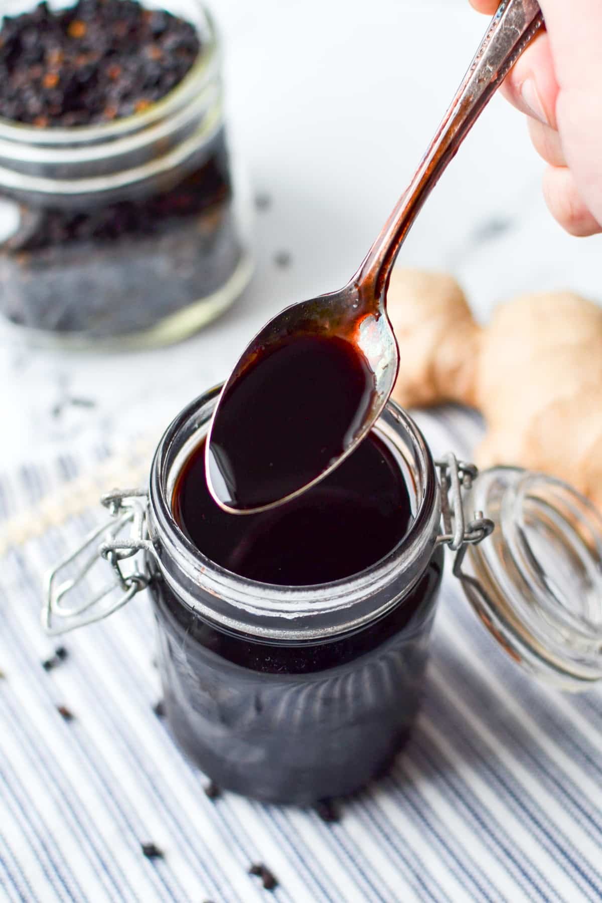 A spoon being taken from a jar of elderberry syrup.