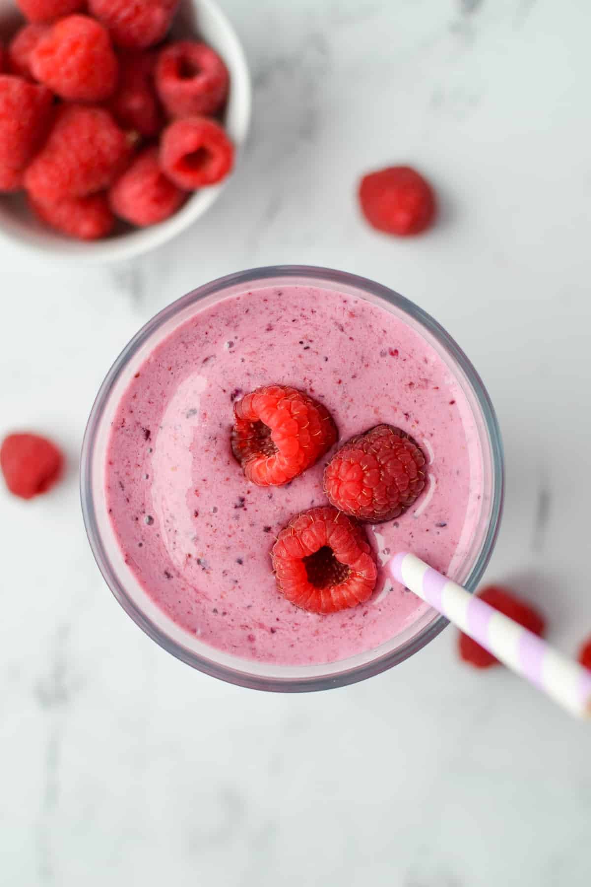 A glass filled with blended fruit and topped with fresh raspberries.