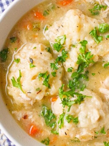 A bowl of chicken stew with dumplings on top.