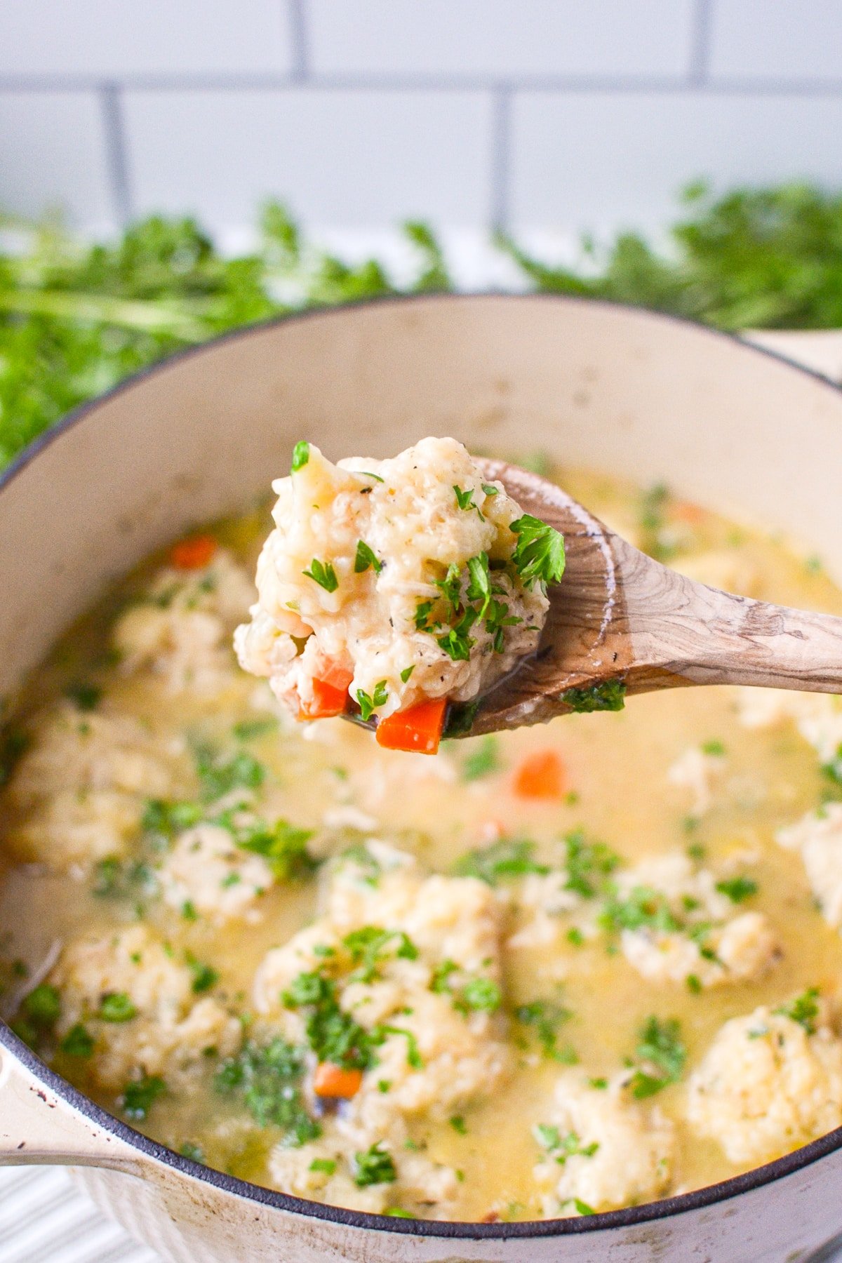 A Dutch Oven with a spoon lifting out a dumpling.