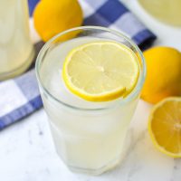 A glass of lemonade finished with a garnish of a slice of lemon.