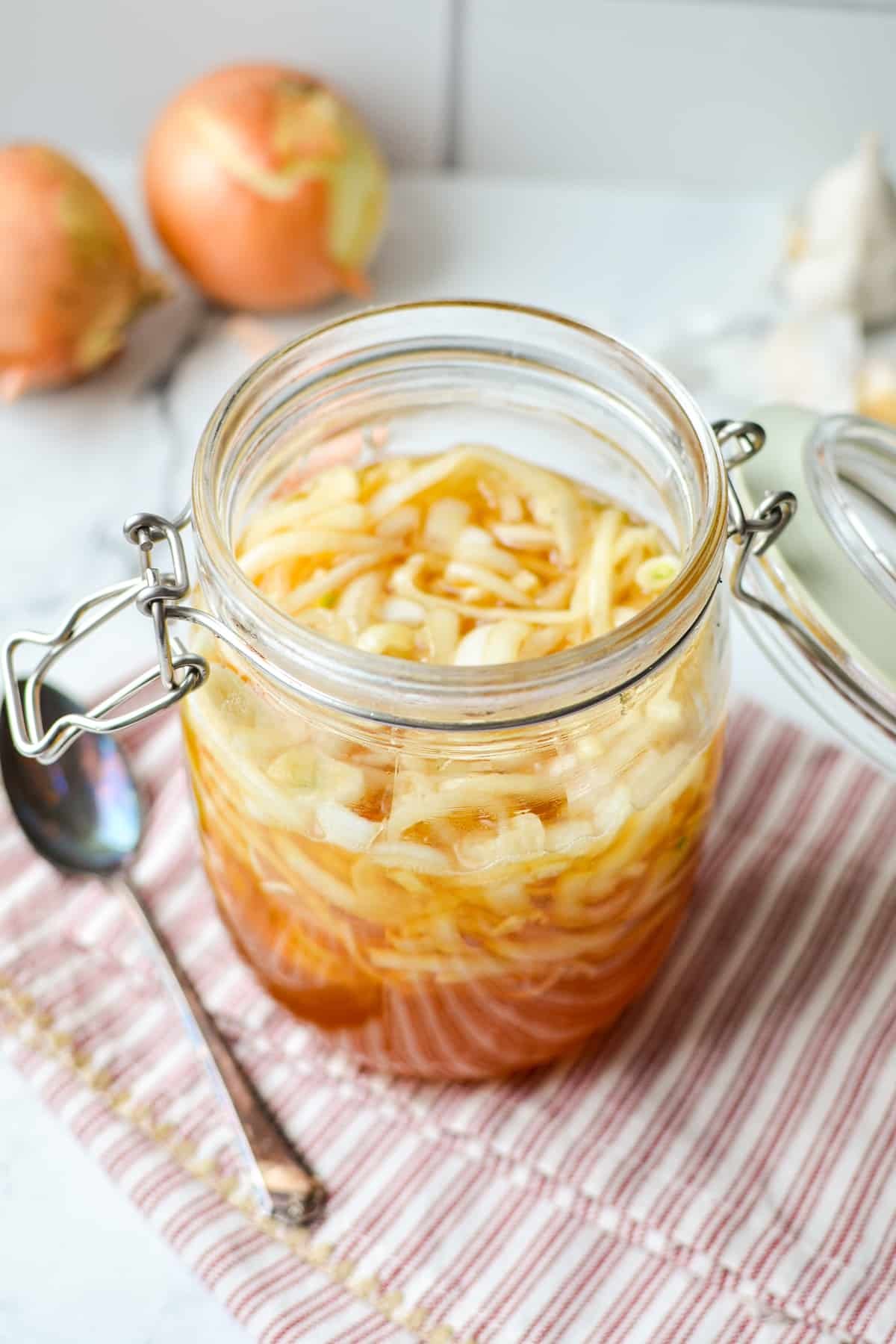 A jar with honey and softened onions with a spoon on the side.