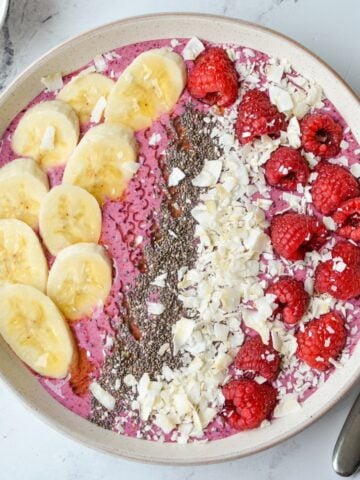 An overhead shot of a smoothie bowl, topped with fruit, chia, and coconut.