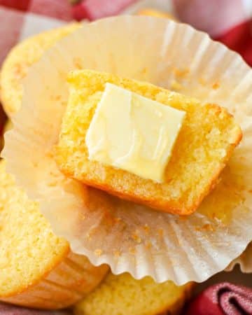 A corn muffin half with a pat of butter on one half.