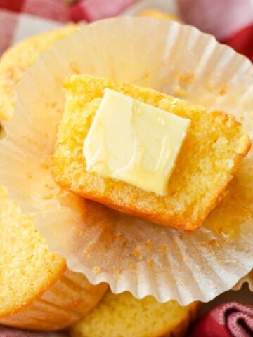 A corn muffin half with a pat of butter on one half.