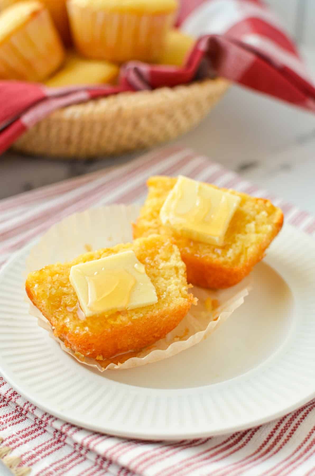 A corn muffin split in half with a pat of butter on each half.