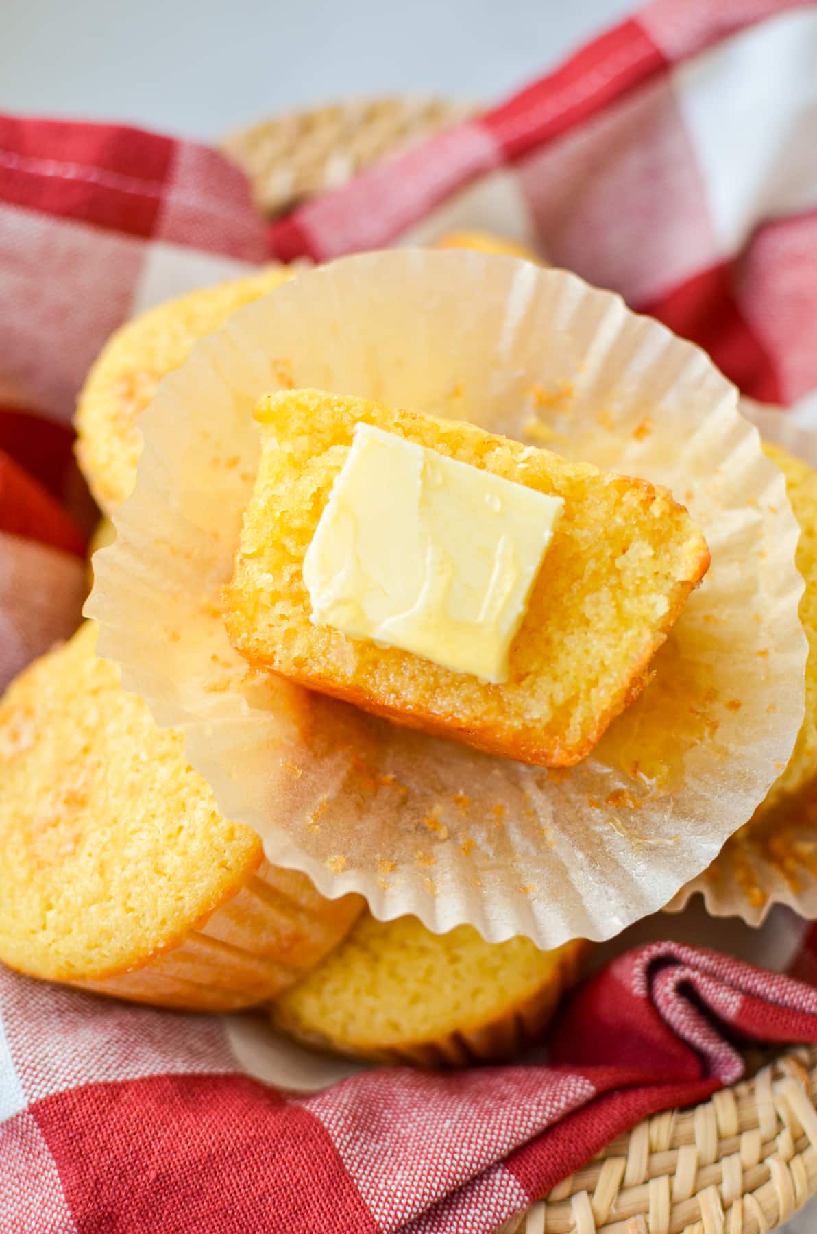 A corn muffin with a pat of butter and drizzle of honey.