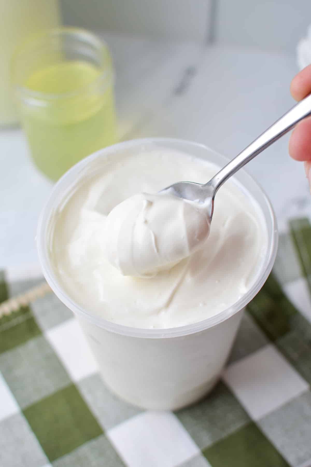 A container of yogurt with a spoon taking a portion.