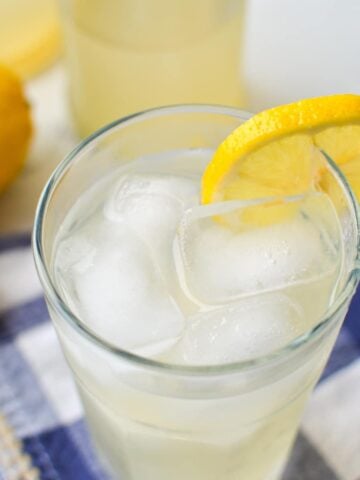 A glass of water kefir, garnished with a fresh lemon slice.