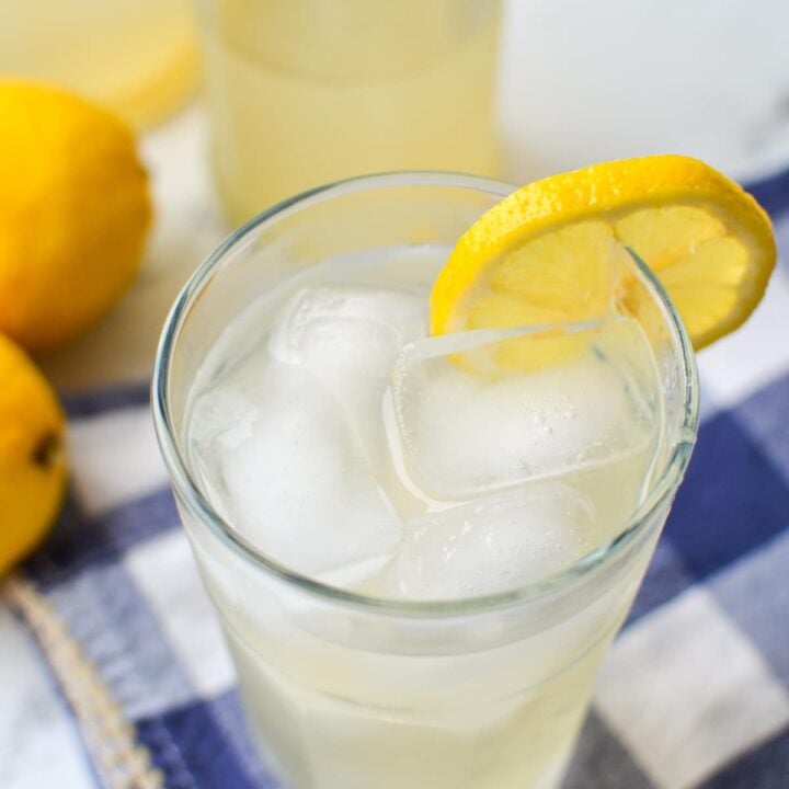 A glass of water kefir, garnished with a fresh lemon slice.