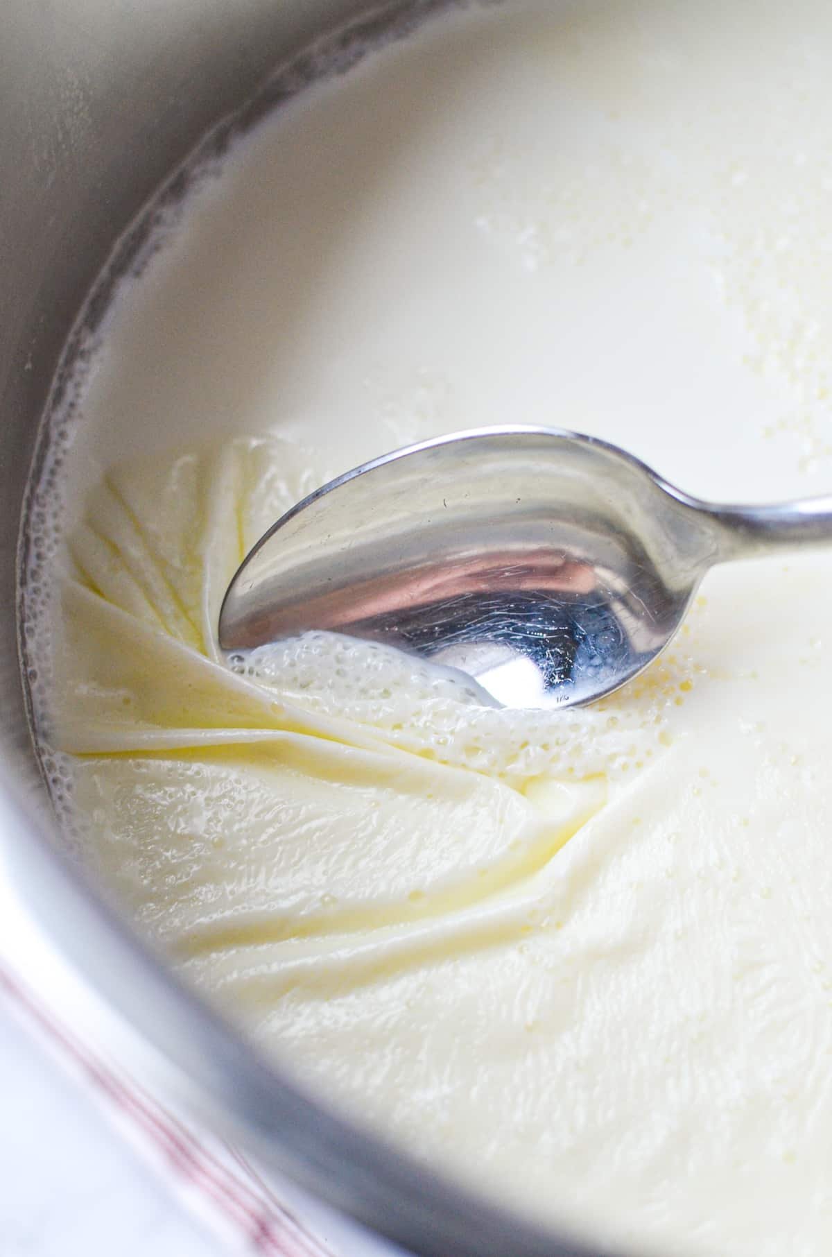 Removing a layer of skin from a large pot of hot milk.