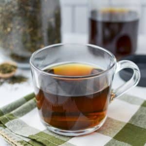 A glass mug full of herbal tea.