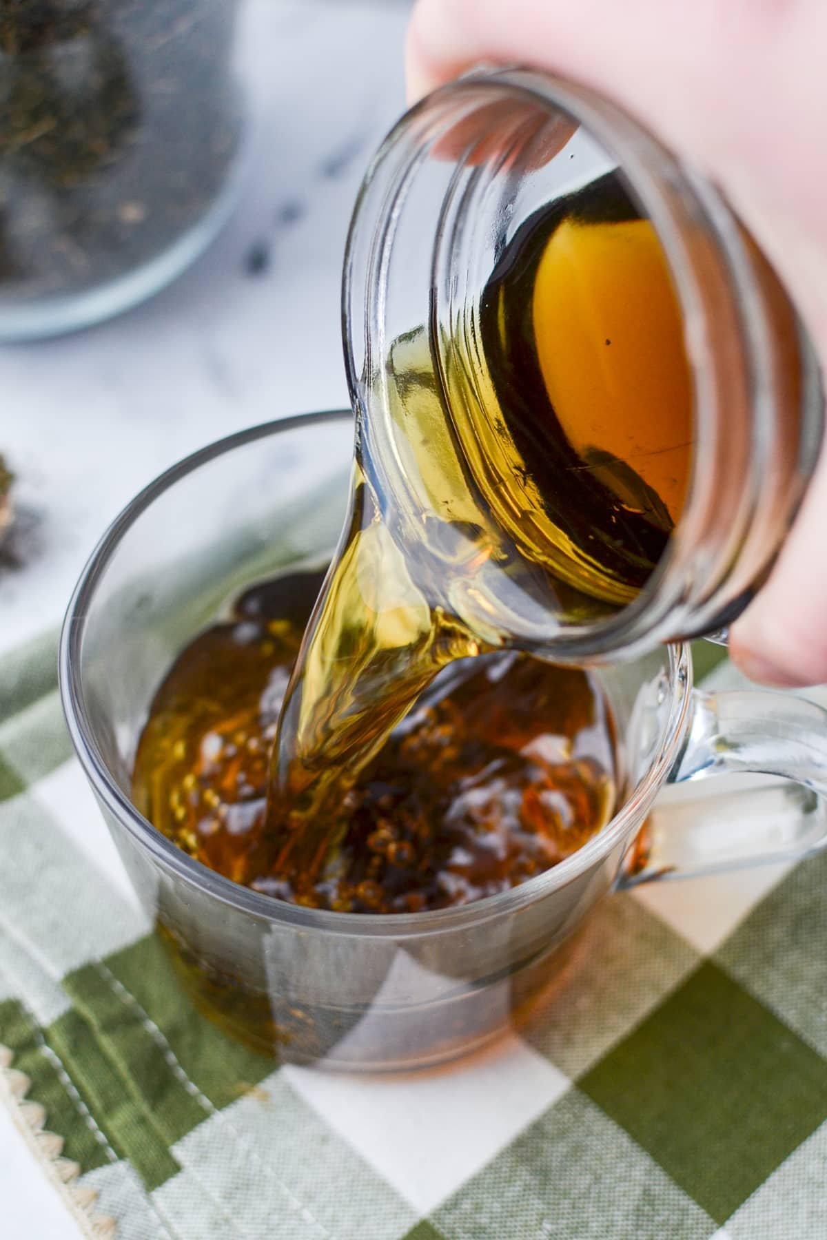 Pouring herbal tea into a glass mug.