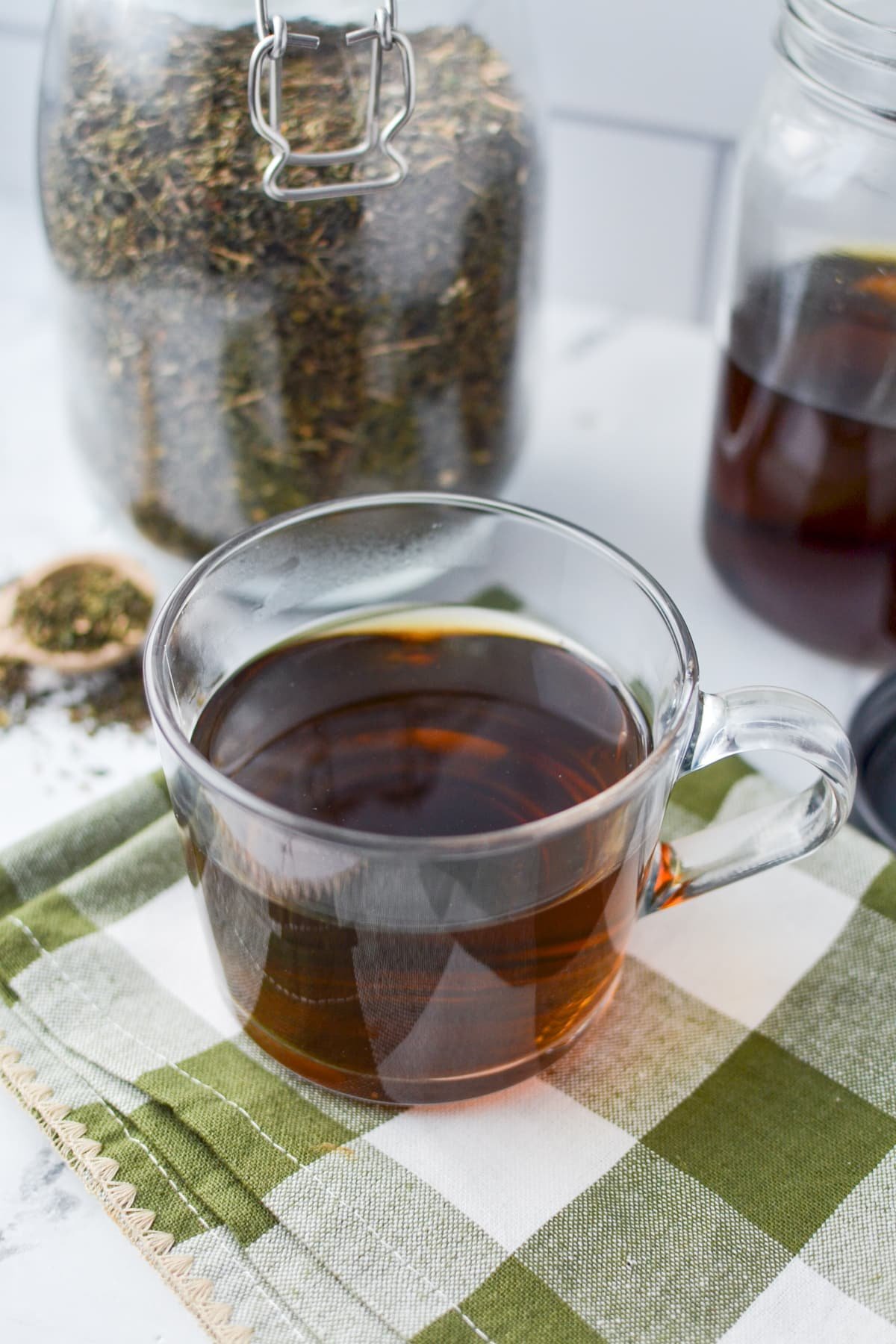 A mug of herbal tea on a green check napkin.