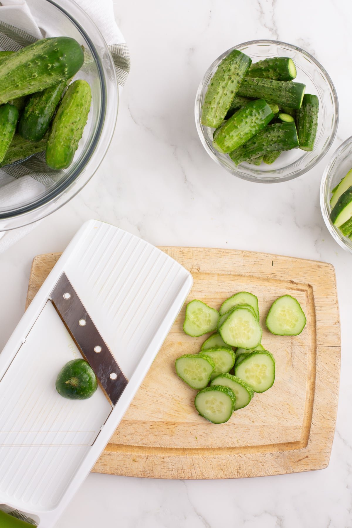 Using a mandolin to slice cucumbers into chips.