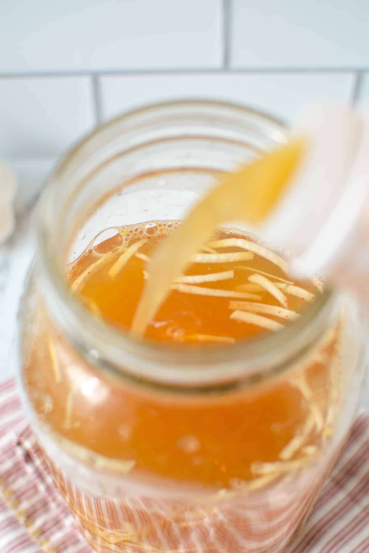 Pouring vinegar into a large mason jar.