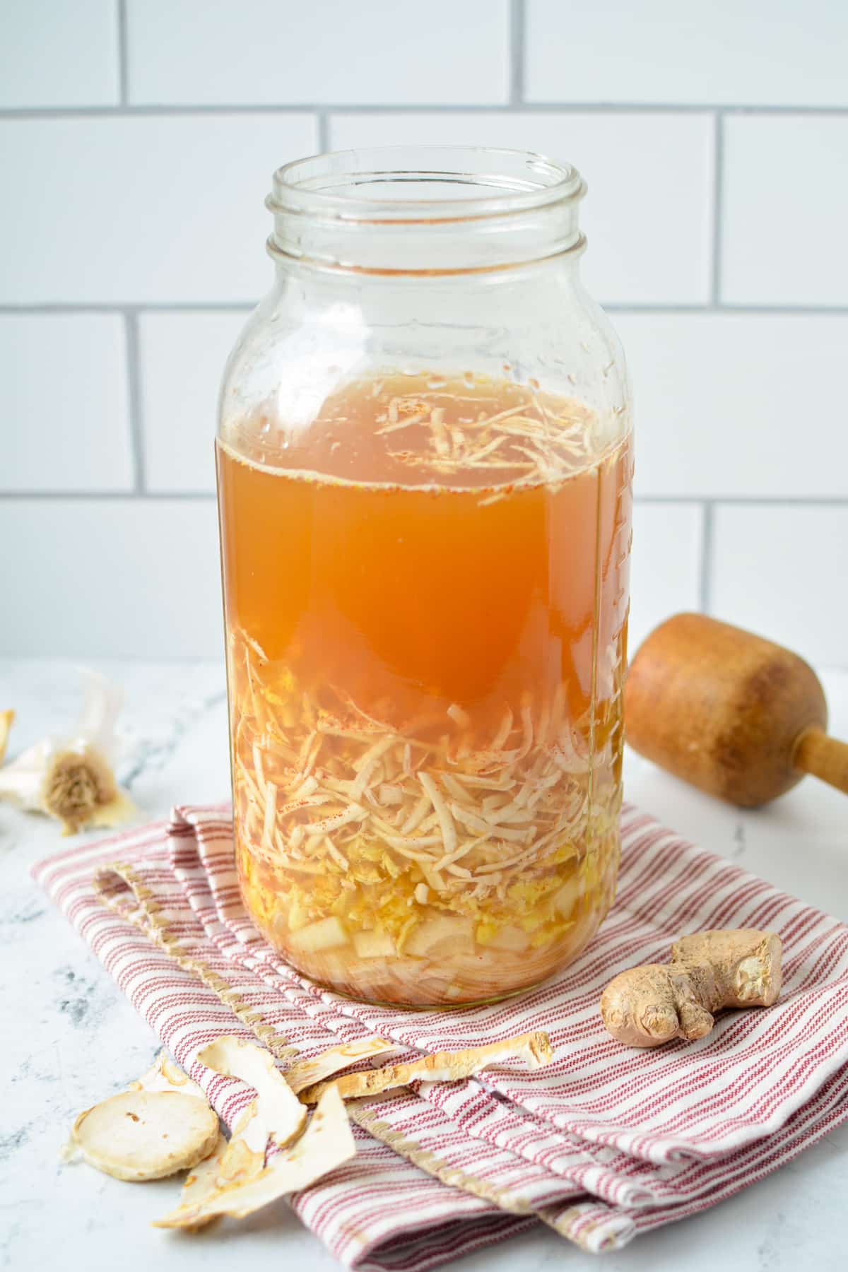 A large mason jar containing shredded horseradish and ginger, and topped off with apple cider vinegar.